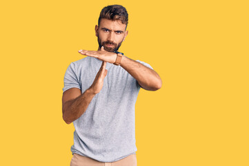 Young hispanic man wearing casual clothes doing time out gesture with hands, frustrated and serious face