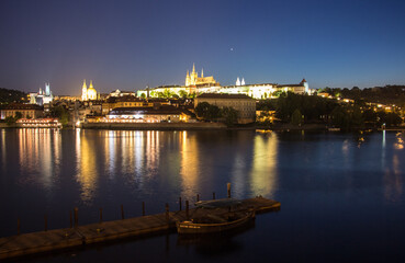 Fototapeta na wymiar Pargue charles bridge and prague castle by night reflections river with boat motive in the front