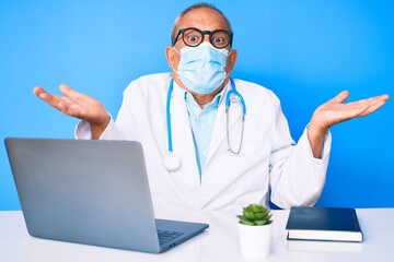Senior handsome man with gray hair wearing doctor uniform and medical mask clueless and confused...