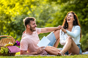 Beautiful young couple enjoying in good books and picnic day in the park. Love and tenderness,...