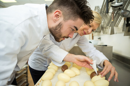 confectioners decorating white chocolate eggs