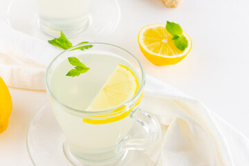 Ginger tea with lemon and mint on a white napkin. Two cups of ginger tea, lemon, ginger root and honey on white background. Top view