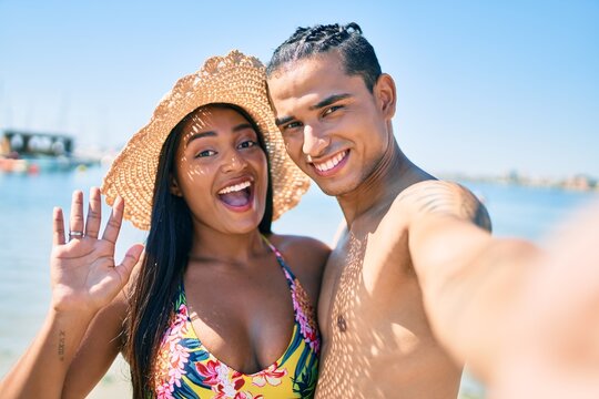 Young latin couple smiling happy making selfie by the camera at the beach.