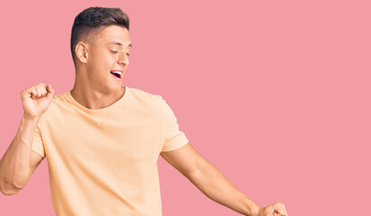 Young handsome man wearing casual clothes dancing happy and cheerful, smiling moving casual and confident listening to music