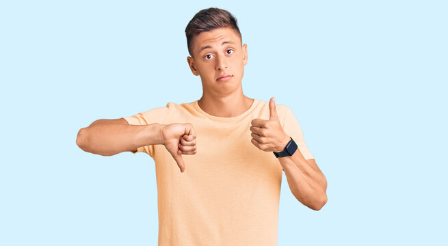 Young handsome man wearing casual clothes doing thumbs up and down, disagreement and agreement expression. crazy conflict