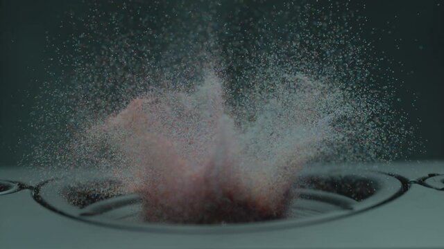Colored Particles fly up in the air as a speaker moves