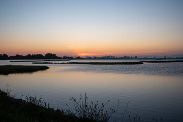 Sunrise over a salt marsh with Ocean City, Maryland silhouetted in the background.