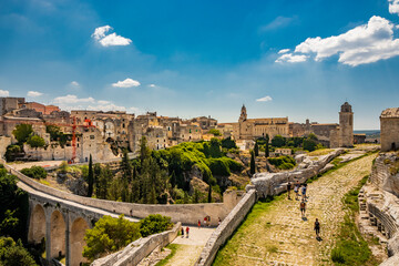 Gravina in Puglia, Italy. The stone bridge, ancient aqueduct and viaduct. Across the valley the skyline of the city with its houses and buildings and the cathedral at the bottom.