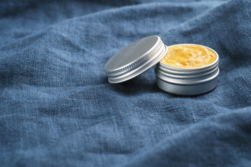 Jar of natural cosmetic product on blue linen fabric