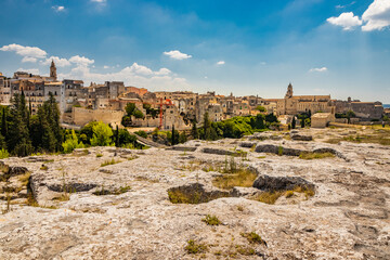 Gravina in Puglia, Italy. The archaeological park of Botromagno at the top of the hill with cave houses and cave churches. The skyline of the city with its houses and palaces and the cathedral.