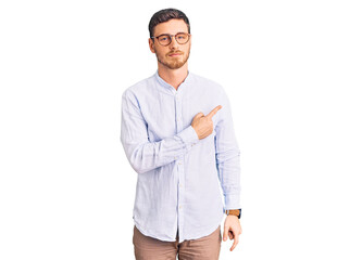 Fototapeta premium Handsome young man with bear wearing elegant business shirt and glasses pointing with hand finger to the side showing advertisement, serious and calm face