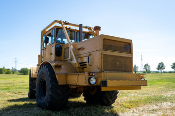 Closeup of a yellow tractor with heavy wheels in a field