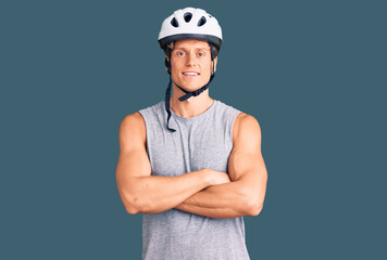 Young handsome man wearing bike helmet happy face smiling with crossed arms looking at the camera. positive person.