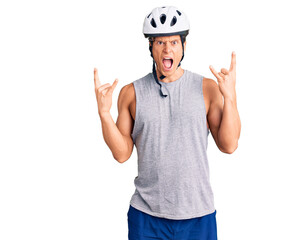Young handsome man wearing bike helmet shouting with crazy expression doing rock symbol with hands up. music star. heavy concept.