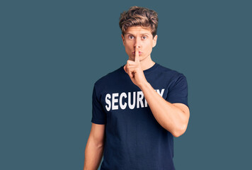 Young handsome man wearing security t shirt asking to be quiet with finger on lips. silence and secret concept.