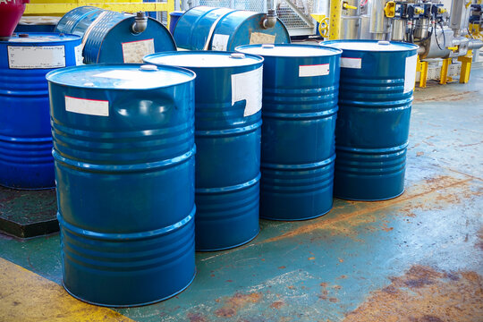 Blue oil drums in front of a factory or industrial plant for oil and gas industry concept.