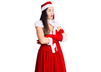 Young beautiful caucasian woman wearing santa claus costume looking to the side with arms crossed convinced and confident