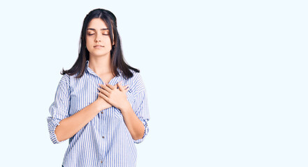 Young beautiful girl wearing striped shirt smiling with hands on chest with closed eyes and grateful gesture on face. health concept.