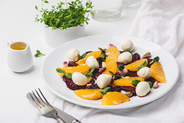 plate of salad with mozzarella, orange, caramelized beetroot and pistachios. 