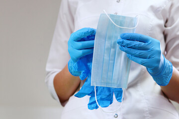 A doctor's assistant is holding a medical mask. Preparing the office for receiving patients. Concept of hygiene and sanitation in the clinic. Disinfection in the dental office. Unrecognizable person.