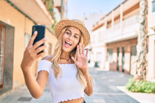 Young blonde tourist girl smiling happy doing video call using smartphone at the city.