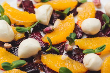 closeup salad mozzarella, orange, caramelized beetroot, sprouted sunflower and pistachios.