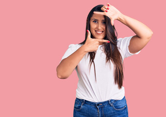 Young beautiful brunette woman wearing casual t-shirt smiling making frame with hands and fingers with happy face. creativity and photography concept.