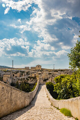 Fototapeta na wymiar Gravina in Puglia, Italy. The stone bridge, ancient aqueduct and viaduct, over the Gravina stream. The Madonna della Stella Sanctuary, with its bell tower and the ancient cave church.