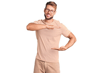 Fototapeta premium Young caucasian man wearing casual clothes and glasses gesturing with hands showing big and large size sign, measure symbol. smiling looking at the camera. measuring concept.