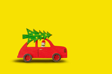 toy wooden red car with Christmas tree on the roof and snowman at the wheel on yellow background