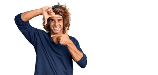 Young hispanic man wearing casual clothes smiling making frame with hands and fingers with happy face. creativity and photography concept.