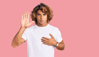 Young hispanic man wearing casual white tshirt swearing with hand on chest and open palm, making a...