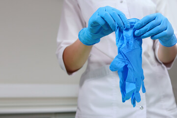 The nurse is holding protective gloves. Preparing the office for receiving patients. Disinfection in the dental office. Unrecognizable person.