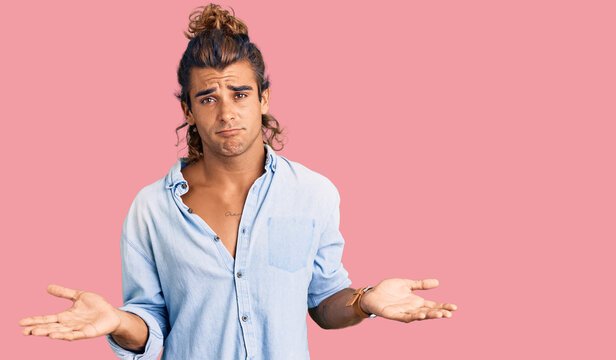 Young hispanic man wearing summer style clueless and confused with open arms, no idea concept.