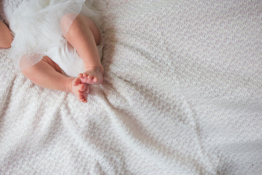 Small feet of a newborn baby on a white sheet. Dry feet in a child.