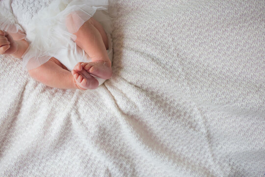 Small feet of a newborn baby on a white sheet. Dry feet in a child.