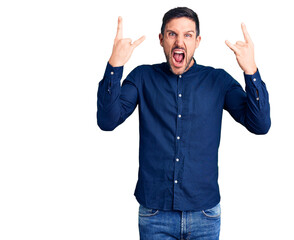 Naklejka premium Young handsome man wearing casual shirt shouting with crazy expression doing rock symbol with hands up. music star. heavy music concept.