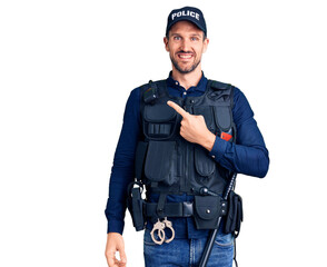 Young handsome man wearing police uniform cheerful with a smile on face pointing with hand and finger up to the side with happy and natural expression