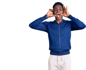 Young african american man wearing sportswear smiling cheerful playing peek a boo with hands showing face. surprised and exited