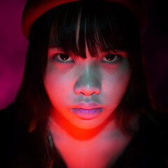 The serious girl wears a red beanie in pink light vibe