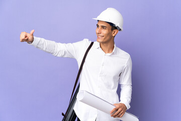 Young architect man isolated on background giving a thumbs up gesture