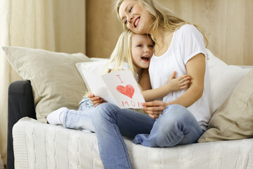 Fototapeta premium Happy mother day. Child daughter congratulates mom and gives her postcard with heart drawing. Family and childhood concepts