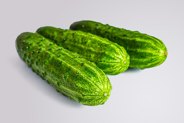 Three green cucumbers on a light background