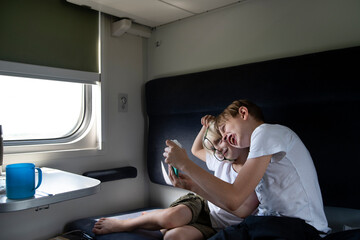 Two boys fool around in compartment carriage. Children in railroad car. Entertainment for young passengers.