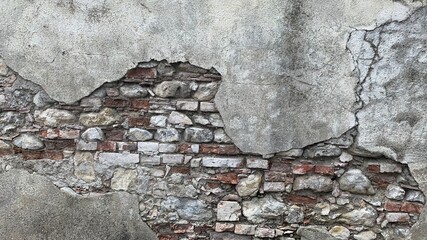 Old grey concrete wall with bricks,big stones with layers of cement between them.Medieval masonry.Background texture in the style of steam punk or loft.Template for design.European piece of fortress