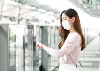 Fototapeta premium Woman wearing face mask and waiting for a train while standing on railway station