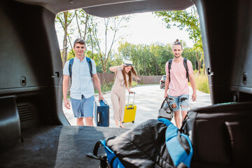 friends load car trunk with baggage