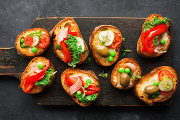 Finger food. Appetizing crostini with baked capsicum, green peas, bacon, kale and lettuce as a festive snack. Top view,