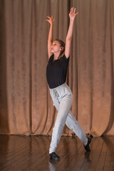 A young dancer rehearsing a dance on stage.