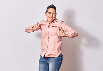 Young beautiful caucaisan woman with short hair wearing casual clothes smiling happy. Jumping with smile on face doing ok sign with thumbs up over isolated white background